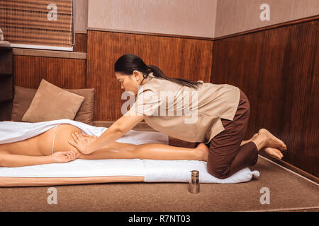 Serious female masseuse massaging her clients body Stock Photo