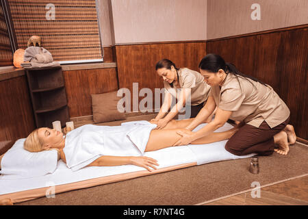 Skilled Thai massage therapists massaging female legs Stock Photo