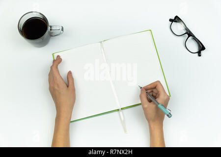 Creating new ideas concept. Top view of female hands writing in a copy book on white table Stock Photo