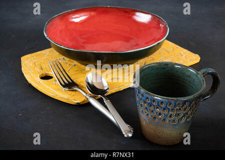 Handmade clay dishes of different colors. on black concrete. dishes, cups. antique cutting board. set for food. Stock Photo