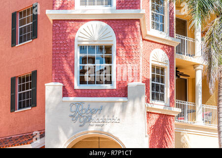 Naples, USA - April 30, 2018: Bayfront pink, red, orange colorful condos, condominiums and sign for Robert of Philadelphia hair design building with p Stock Photo
