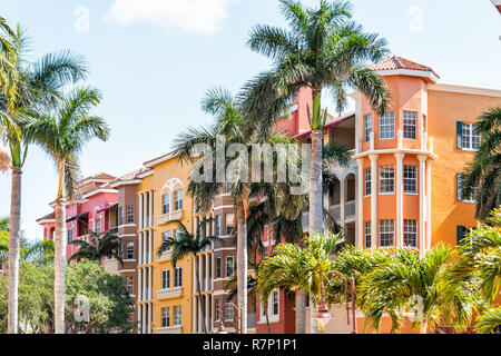 Naples, USA - April 30, 2018: Bayfront orange condo, condominium building with palm trees in community shopping center, sky Stock Photo