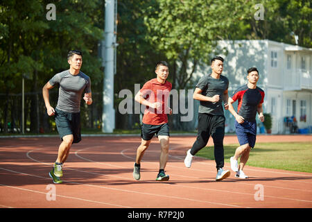 a group of four young asian athletes training on track. Stock Photo