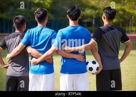 outdoor portrait of a team of young asian soccer football players, rear view Stock Photo