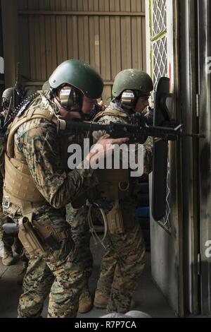 U.S. Marine Corps Lance Cpls. Jackson Stumb, left, and Benjamin Irish, right, Special Reaction Team (SRT) members for Marine Corps Air Station (MCAS) Iwakuni, conduct breaching techniques during cross training exercises with the Hiroshima and Yamaguchi Prefectural Police Headquarters at MCAS Iwakuni, Japan, March 28, 2017. Members with the Hiroshima and Yamaguchi Prefectural Police Headquarters traveled to the air station to observe SRT conduct high-risk training scenarios. The training ranged from room-clearing, breaching, communication and non-lethal take-down techniques. Stock Photo