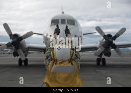 OAK HARBOR, Wash. (March 27, 2017) Aviation Electronics Technician 3rd Class Kerry Fee, assigned to Patrol Squadron (VP) 40, signals to a P-3C Orion while launching the aircraft onboard Naval Air Station Whidbey Island. All positions on the aircraft were occupied by Female Sailors. Stock Photo