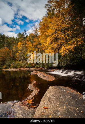 colorful fall foliage forest and river landscape with a small waterfall in the Appalachians of North Carolina near Triple Falls in DuPont State Forest Stock Photo