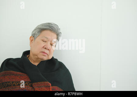 elder woman taking a nap. asian elderly female senior napping sleeping near white wall Stock Photo