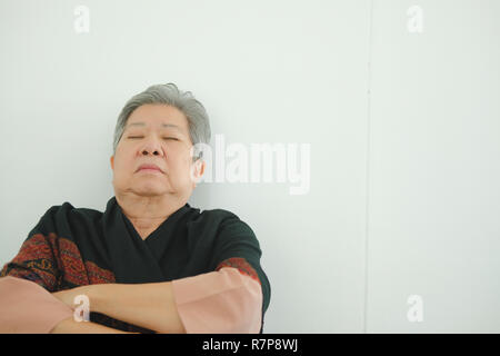 elder woman taking a nap. asian elderly female senior napping sleeping near white wall Stock Photo