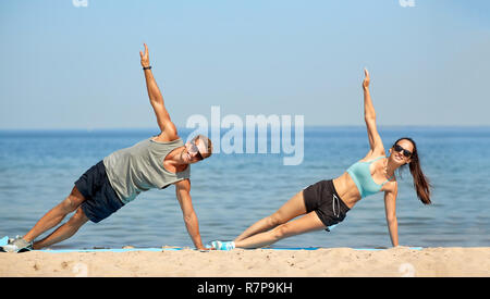 couple doing side plank exercise on summer beach Stock Photo