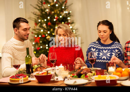 friends praying before christmas dinner at home  Stock Photo