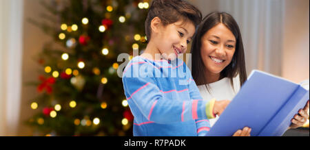 mother and daughter reading book on christmas Stock Photo