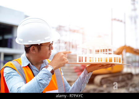 Asian engineer architects working on new architectural house model. Designers looking at house model outdoor. Stock Photo