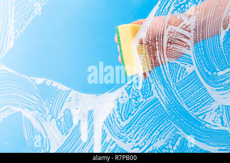 Hand cleaning glass window pane with detergent by sponge. Stock Photo