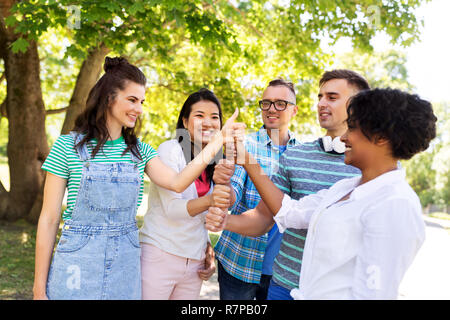 happy friends making thumbs up in park Stock Photo
