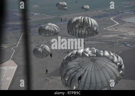 Bulgarian paratroopers descend from a C-130J Super Hercules during Exercise Thracian Spring 17 at Plovdiv Regional Airport, Bulgaria, March 20, 2017. Airmen from the 37th Airlift Squadron, 435th Contingency Response Group, and 86th Airlift Wing, Ramstein Air Base, Germany, partnered with the Bulgarian military for the two-week exercise. The U.S. Air Force’s forward presence in Europe allows Airmen to work hand-in-hand with Allies to develop and improve ready air forces that are capable of maintaining regional security. Stock Photo