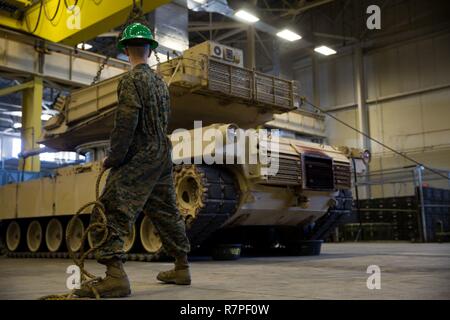 A Marine holds a rope to help steady an M1A1 Abrams tank’s 120 mm turret before setting it onto its frame at Camp Lejeune, N.C., Mar. 23, 2017. The Marines with 2nd Maintenance Battalion, 2nd Marine Logistics Group and 2nd Tank Battalion, 2nd Marine Division removed the tanks’ turrets to replace their nuclear, biological and chemical seals. The Marine is with 2nd Maintenance Bn. Stock Photo