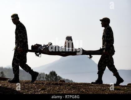 Two Nepalese soldiers carry a role player acting as a wounded casualty during a mass casualty training drill during exercise Shanti Prayas in Nepal. Shanti Prayas is a multinational United Nations peacekeeping exercise designed to provide pre-deployment training to U.N. partner countries in preparation for real-world peacekeeping operations. Stock Photo