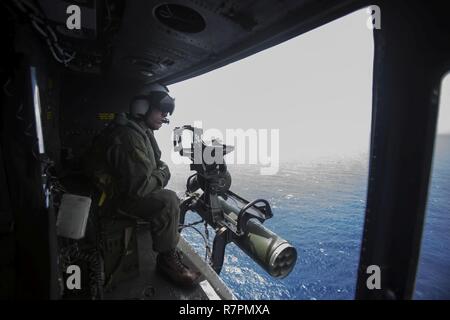 Lance Cpl. Jacob Miller, a crew chief with Marine Light Attack Helicopter Squadron 367, stares outside the hatch of a UH-1Y helicopter off the shores of MCB Hawaii prior to conducting a funeral flyover on March 24, 2017. The helicopters flew in a missing man formation, in honor of retired Marine Col. Vincil W. Hazelbaker, a decorated aviator and Navy Cross recipient. Stock Photo