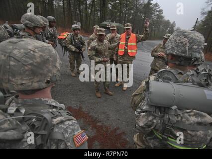 U.S. Army Soldiers from the New Jersey Army National Guard listen to a safety briefing before starting a 12-mile timed ruck march during the 2017 New Jersey Army National Guard Best Warrior Competition on Joint Base McGuire-Dix-Lakehurst, N.J., March 28, 2017. Eight Soldiers and eight NCOs are competing in the NJARNG’s Best Warrior Competition, Mar. 27-29, which features timed events, including urban warfare simulations, a 12-mile ruck march, land navigation, and the Army Physical Fitness Test. The top Soldier and NCO will go on to compete in the Region 1 Competition in April against National  Stock Photo