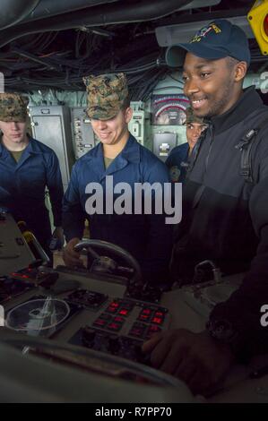 PHILIPPINE SEA (March 28, 2017) Cpl. Aaron Briggs, from New Orleans, mans the helm under the instruction of Boatswain’s Mate Seaman Ahmed Jamjalloh, from Alexandria, Va., on the bridge of the amphibious assault ship USS Bonhomme Richard (LHD 6). Bonhomme Richard, flagship of the Bonhomme Richard Expeditionary Strike Group, with embarked 31st Marine Expeditionary Unit, is on a routine patrol, operating in the Indo-Asia-Pacific region to enhance warfighting readiness and posture forward as a ready-response force for any type of contingency.
