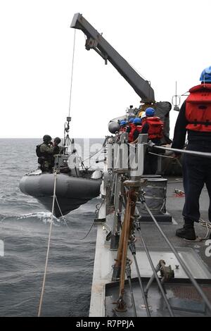 ARABIAN GULF (March 24, 2017) Sailors, assigned to the guided-missile destroyer USS Cole (DDG 67), board a rigid-hull inflatable boat during an approach and assist visit with a United Arab Emirates-flagged vessel. Cole is deployed in the U.S. 5th Fleet area of operations in support of maritime security operations designed to reassure allies and partners, and to preserve the freedom of navigation and the free flow of commerce in the region. Stock Photo