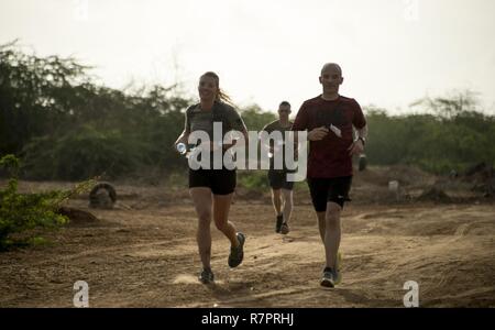 U.S. Air Force 1st Lt. Elizabeth Holloway and U.S. Army Col. Jason Musteen participate in the running portion of the Joint Warrior Competition (JWC) outside of Camp Lemonnier, Djibouti, March 25, 2017. Participants in the JWC test themselves physically in various events including a four kilometer timed run. Stock Photo