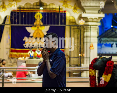 Singapore, Singapore. 11th Dec, 2018. A man prays at the Sri Sivan Temple in the Geylang neighborhood. The temple was originally built in 1850s in the area that in now Orchard Road. The temple was moved to its current site in Geylang in 1993. The Geylang area of Singapore, between the Central Business District and Changi Airport, was originally coconut plantations and Malay villages. During Singapore's boom the coconut plantations and other farms were pushed out and now the area is a working class community of Malay, Indian and Chinese people. In the 2000s, developers started gentrifying Stock Photo