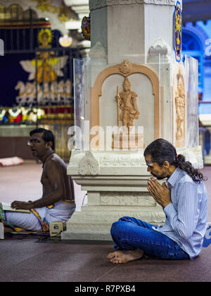 Singapore, Singapore. 11th Dec, 2018. A man prays at the Sri Sivan Temple in the Geylang neighborhood. The temple was originally built in 1850s in the area that in now Orchard Road. The temple was moved to its current site in Geylang in 1993. The Geylang area of Singapore, between the Central Business District and Changi Airport, was originally coconut plantations and Malay villages. During Singapore's boom the coconut plantations and other farms were pushed out and now the area is a working class community of Malay, Indian and Chinese people. In the 2000s, developers started gentrifying Stock Photo