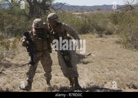 U.S. Marine Corps Pfc. Luis J. Brito, left, a rifleman with 1st Platoon, Echo Company, 2nd Battalion, 6th Marine Regiment, 2nd Marine Division (2d MARDIV), assists a simulated casualty out of a simulated improvised explosive device (IED) impact area during counter-IED training on Forward Operating Base Laguna, U.S. Army Yuma Proving Grounds for Talon Exercise (TalonEx) 2-17, Yuma, A.Z., March 28, 2017. The purpose of TalonEx was for ground combat units to conduct integrated training in support of the Weapons and Tactics Instructor Course (WTI) 2-17 hosted by Marine Aviation Weapons and Tactics Stock Photo