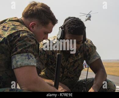 U.S. Marine Corps Lance Cpls. Kevin McKee, left, and Byron Armstrong, right, communications technicians with Marine Air Control Squadron (MACS) 4, talk to Japan Maritime Self-Defense Force helicopter pilots during a cross-training exercise at Marine Corps Air Station Iwakuni, Japan, March 30, 2017. The Marines took part in a simulated forward arming and refueling points operation, where they communicated with JMSDF helicopter pilots to perform austere landings on a heliport that acted as an expeditionary runway. Stock Photo