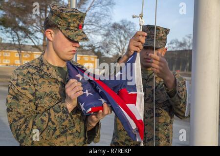 U.S. Marines Lance Cpl. Jack Tashjian and Lance Cpl. Austin Robinson, a landing support specialist and warehouse clerk respectively, fly the American flag at Vaernes Garnison, March 30, 2017. Marine Rotational Force Europe 17.1 (MRF-E) upholds traditions during its stay in Norway, facilitating military exercises in the region in support of NATO. Stock Photo