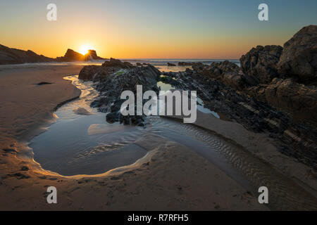 Rocks and rock pool on beach at low tide at sunset, Zambujeira do Mar, Alentejo region, Portugal, Europe Stock Photo