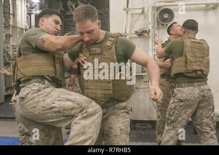 USS SOMERSET, At Sea (March 27, 2017) U.S. Marine Cpl. Jeovanni Saucedo, an infantry rifleman with Light Armored Reconnaissance Company, Battalion Landing Team 1st Bn., 4th Marines, 11th Marine Expeditionary Unit (MEU), executes a knee strike to the abdomen during a Marine Corps Martial Arts Program (MCMAP) training session aboard USS Somerset (LPD 25), March 27. MCMAP teaches Marines combative skills and reinforces the Marine Corps principles and leadership traits through professional military education tie-ins throughout the course. The 11th MEU provides a sea-based, Marine Air-Ground Task F Stock Photo