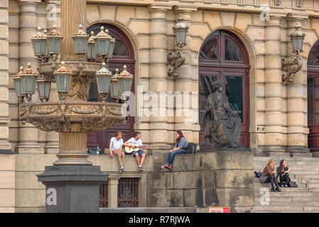 Young people talking, view of young people talking while sitting outside the Rudolfinum concert hall building in Prague, Czech Republic. Stock Photo