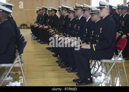 NEWPORT, R.I. (March 31, 2017) Officer candidates await their official appointment as Navy ensigns during an officer candidate school graduation held at Kay Hall onboard Naval Station Newport, Rhode Island. Eighty-one officer candidates participated in the ceremony. The mission of OCS is to develop civilians, enlisted and newly commissioned personnel morally, mentally and physically and imbue them with the highest ideals of honor, courage and commitment in order to prepare them for service in the fleet as Naval officers. Stock Photo