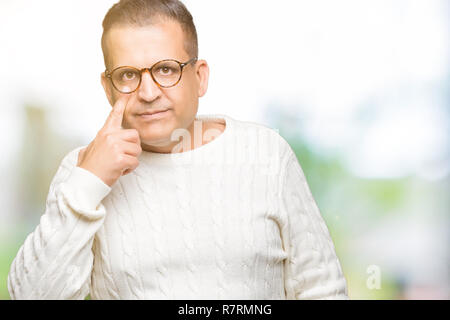 Middle age arab man wearing glasses over isolated background Pointing to the eye watching you gesture, suspicious expression Stock Photo