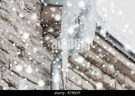 icicles hanging from building drainpipe Stock Photo