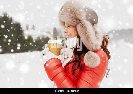 happy woman in winter fur hat with coffee outdoors Stock Photo