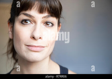 Young woman close-up portrait. Caucasian with brown long hair and bangs with ponytail. Smiling expression, copy space. Stock Photo