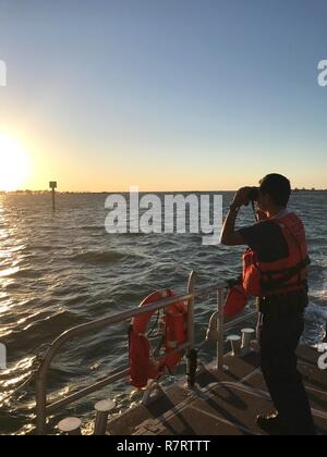 Coast Guard Seaman Sebastian Orozco, a crew member aboard a 45-foot Response Boat-Medium from Station Fort Myers Beach, Florida, searches for a missing kayaker in San Carlos Bay, Florida, Saturday, April 9, 2017. The 29-year-old kayaker went missing after taking his kayak to fish off Punta Rassa April 8. Stock Photo