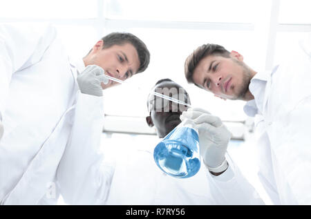 group of scientists examines the liquid in the flask. Stock Photo