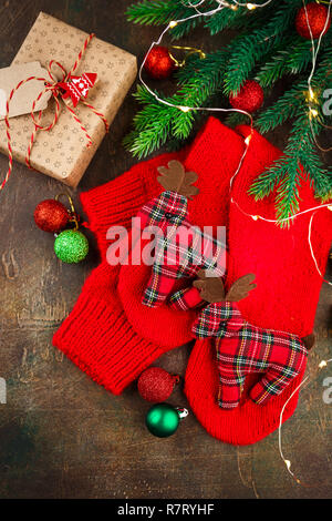 Christmas warm knitted red socks with toy deers. Christmas background with gifts. Top view, flat lay. Stock Photo