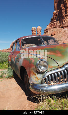 Rusty vintage car, abandoned in the sand in front of the twin rocks of Bluff Stock Photo