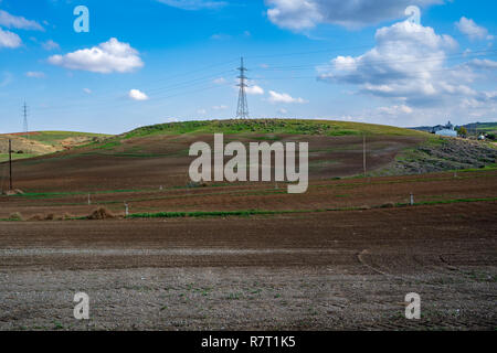Power Pole on a Hill with a blue sky and white clouds Stock Photo