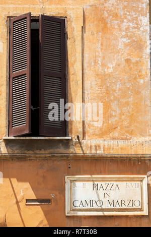 An open wooden shuttered window in a weathered wall in Piazza Campo Marzio in Rome, Italy. Stock Photo