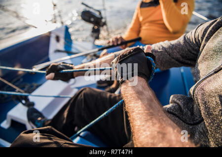 Man and woman hands ulling winch rope on sailing boat Stock Photo