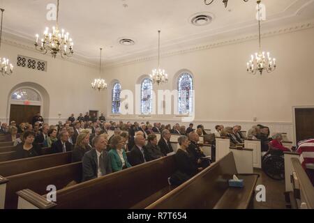 Family and invited guest listen to the benediction during the funeral service of retired Marine Col. John H. Glenn Jr., at the Old Post Chapel, Ft. Myer, Arlington, Va.,  April 6, 2017. Glenn passed away Dec. 8, 2016. Glenn was a U.S. Marine aviator who flew 149 combat missions during World War II and the Korean War. He later became a NASA astronaut and was the first man to orbit the earth aboard the “Friendship 7” in 1962. H was then elected to the U.S. Senate for the state of Ohio in 1974 and served four consecutive terms. Stock Photo