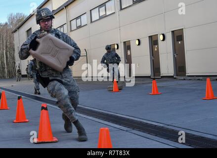 Airman 1st Class Juan Lopez-Rios, 100th Security Forces Squadron patrolman, carries a jug of water while running an obsticale course during the 435th Security Forces Squadron’s Ground Combat Readiness Training Center’s Security Operations Course on Ramstein Air Base, Germany, March 25, 2017. Lopez-Rios ran the obsticle course to elevate his heart rate before doing the Humvee egress training portion of the course where he and four other students were turned upside down in a mock Humvee. Airmen assigned to the 86th SFS, 422nd SFS, 100th SFS, and 569th U.S. Forces Police Squadron participated in  Stock Photo