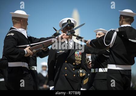 WASHINGTON, DISTRICT OF COLUMBIA -Yeoman Chief Petty Officer Brian Tolentino, a sailor with the United States Navy's Ceremonial Guard walks through two rows of spinning rifles and bayonets during the Joint Service Drill Team Exhibition April 08, 2017, at the Jefferson Memorial in Washington, D.C. Drill teams from all four branches of the U.S. armed forces and the U.S. Coast Guard competed in a display of  skills at the event that celebrated U.S. military heritage at the National Cherry Blossom Festival.     Members of the Navy Ceremonial Guard participate in some of our nation’s most prestigio Stock Photo